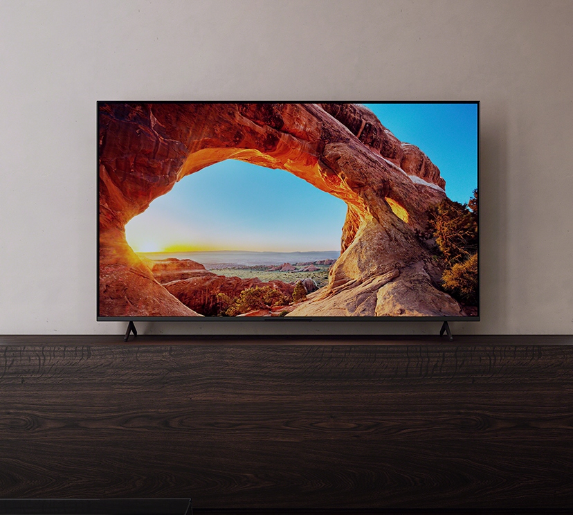Телевизор BRAVIA X85J в гостиной показывает детализированное изображение гор и моря