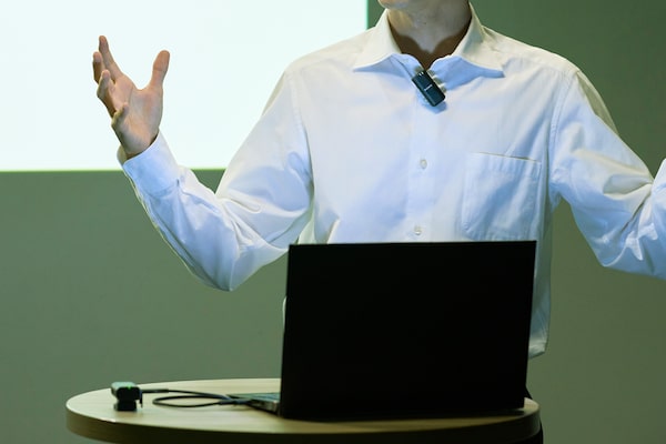 Фотография мужчины, ведущего презентацию, с прикрепленным к одежде микрофоном
