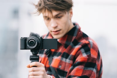 Изображение человека, который держит камеру за основание рукоятки и смотрит в монитор