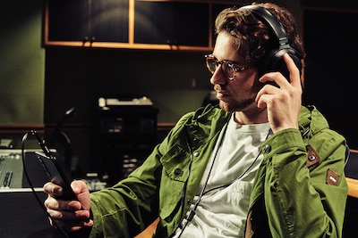 Мужчина в наушниках слушает музыку на Xperia 1 III, находясь в студии