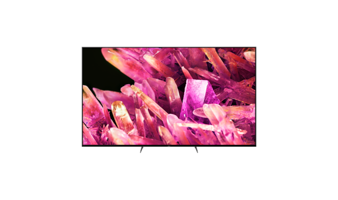 Телевизор BRAVIA X90K на подставке с изображением розовых кристаллов на экране, вид спереди