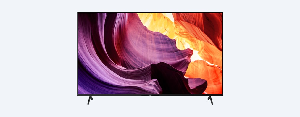 Телевизор BRAVIA X80K с подставкой и изображением фиолетовых и оранжевых объектов на экране, вид спереди