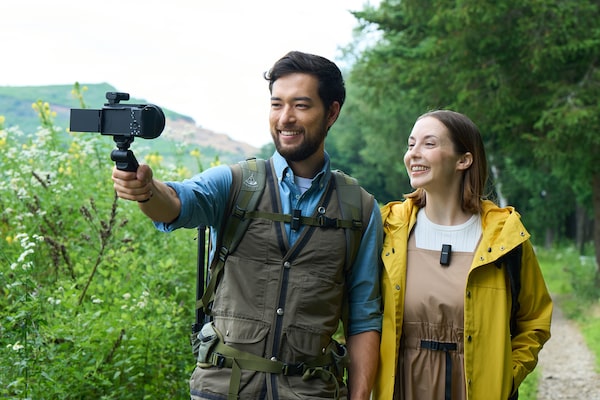 Фотография мужчины и женщины с микрофонами, они улыбаются на камеру, к которой прикреплен приемник