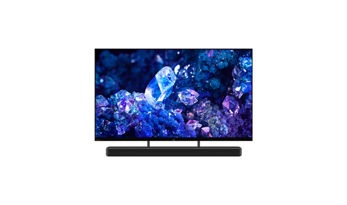 Телевизор BRAVIA A90K с изображением синих и фиолетовых кристаллов на экране и саундбар, вид с угла спереди