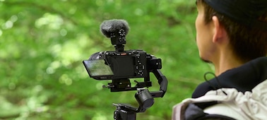 Изображение использования, на котором показан пользователь, снимающий вручную камерой с прикрепленным микрофоном и ветрозащитой