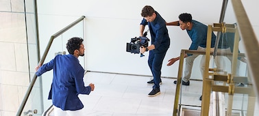 Изображение фотографа, снимающего на камеру мужчину в рамках съемки с участием двух человек.