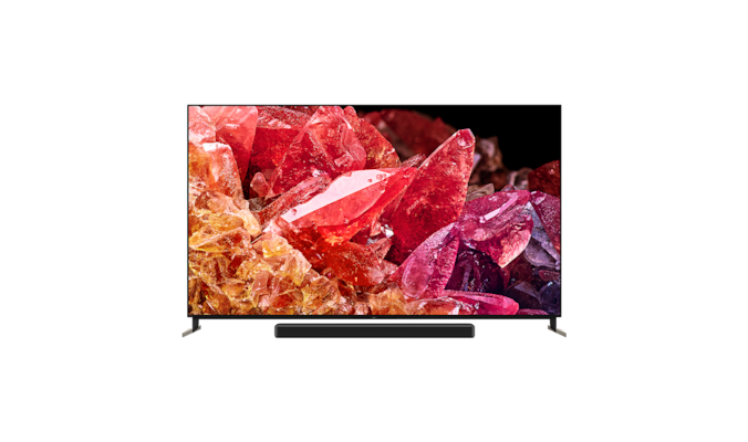 Телевизор BRAVIA X95K на подставке с саундбаром и изображением красных и оранжевых кристаллов на экране, вид спереди