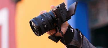 Изображение пользователя, который держит камеру α7C II с объективом FE 24–50 мм F2.8 G сверху, демонстрируя его компактный размер