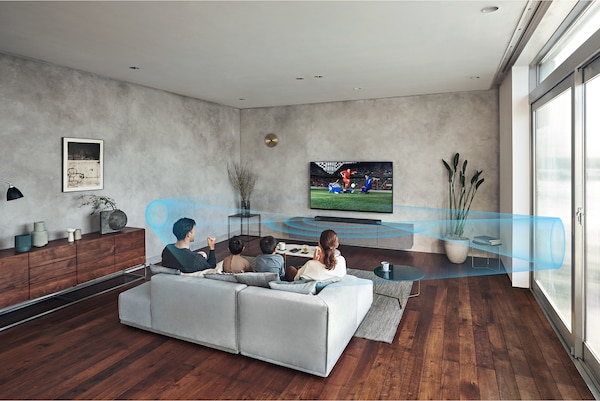 Семья на диване в гостиной смотрит стоящий на мраморной полке телевизор с саундбаром HT-A7000. Улучшение звучания выключено