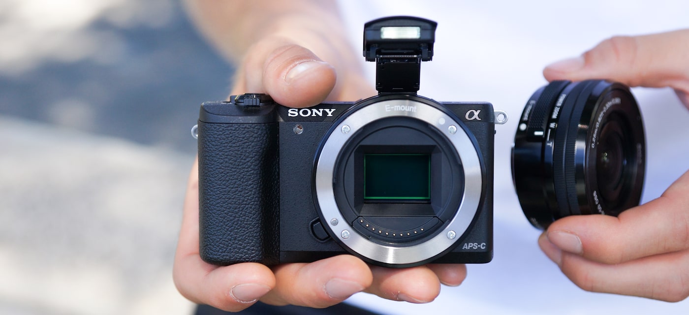 Камера со снятым объективом в руках