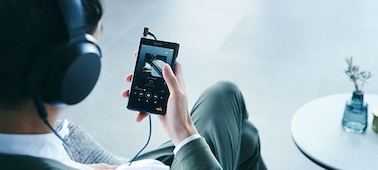 Человек в проводных наушниках слушает музыку на плеере Walkman WM1AM2