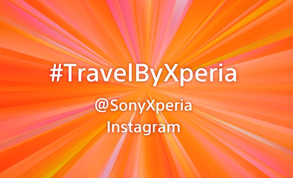 Название кампании #TravelByXperia со ссылкой на официальную страницу в Instagram (@SonyXperia) на оранжевом фоне