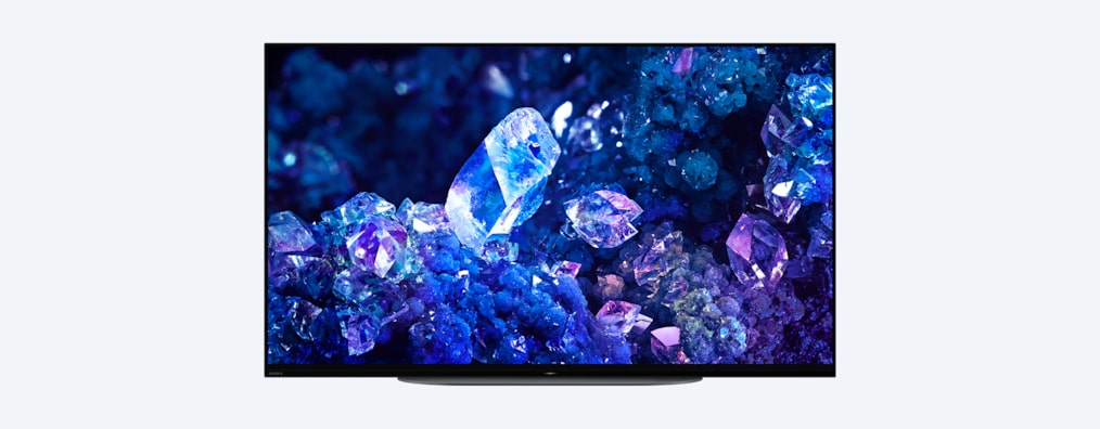 Телевизор BRAVIA A90K с изображением синих и фиолетовых кристаллов на экране, вид спереди