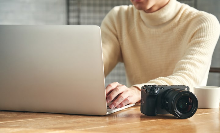 Изображение человека, работающего на компьютере за столом, на котором лежит камера