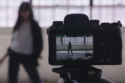 Пример изображения установленной на штатив камеры, на которую снимают видео с женщиной