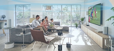 Сидящая на диване семья смотрит установленный на деревянной полке телевизор с домашним кинотеатром HT-A9. Улучшение звука включено, а над комнатой виден купол звуковых волн.