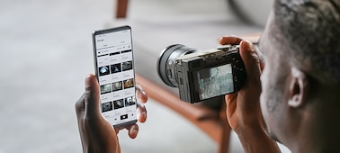 Изображение мужчины, передающего фотографии с камеры на смартфон