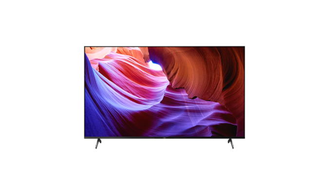 Телевизор BRAVIA X85K с подставкой в широкой позиции и изображением фиолетовых и оранжевых объектов на экране, вид спереди