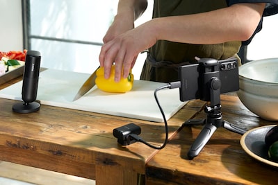Изображение, на котором показан человек, готовящий еду, рядом с которым стоит микрофон с приемником, подключенным к смартфону на стойке через кабель USB