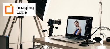 Изображение студии, иллюстрирующее приложение для ПК Imaging Edge, с камерой на штативе и ПК со снимком камеры на экране