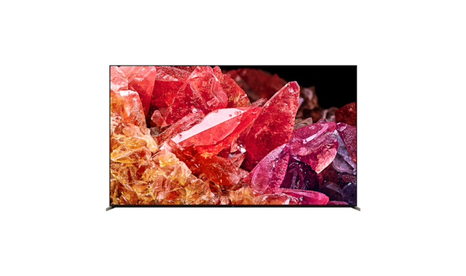 Телевизор BRAVIA X95K на подставке с изображением красных и оранжевых кристаллов на экране, вид спереди
