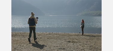 Изображение мужчины, который держит камеру и снимает женщину на пляже