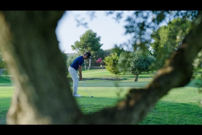 Пример изображения гольфиста в фокусе и расфокусированного ствола дерева на переднем плане