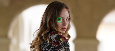 Изображение модели на фоне боке с зеленой рамкой над одним глазом, иллюстрирующее функцию автофокусировки по глазам