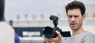 Изображение мужчины, снимающего видео с помощью камеры, которую он держит в руке.