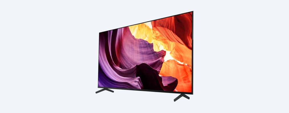 Телевизор BRAVIA X80K с подставкой и изображением фиолетовых и оранжевых объектов на экране, вид сбоку