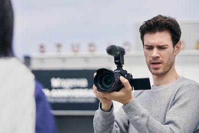 Изображение мужчины, снимающего видео с помощью камеры, которую он держит в руке.
