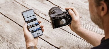Изображение, на котором показан пользователь, передающий изображения с камеры на смартфон
