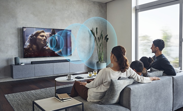 Семья сидит на диване и смотрит телевизор с саундбаром HT-A7000 на мраморной тумбе