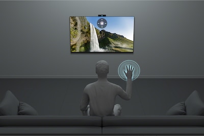 Мужчина использует управление жестами перед телевизором в гостиной.