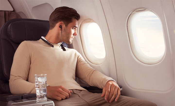 Изображение мужчины, который слушает музыку в наушниках WI-1000XM2 в самолете