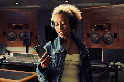 Женщина в наушниках слушает музыку на Xperia 5 III, находясь в студии звукозаписи