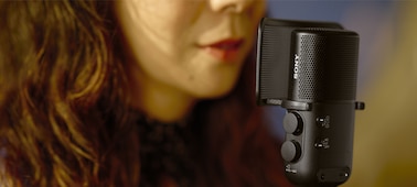 Изображение женщины, которая поет в микрофон, при этом ее рот находится близко к микрофону с поп-фильтром