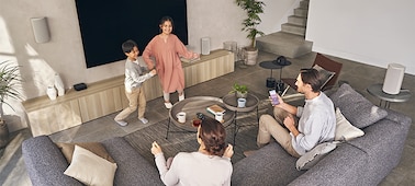 Члены семьи наслаждаются музыкой, сидя и стоя в разных точках комнаты