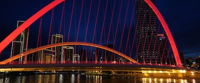 Ночной снимок городского пейзажа с мостом, освещенным красными огнями, на заднем плане