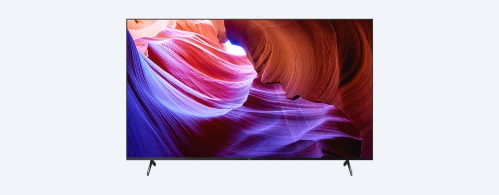 Телевизор BRAVIA X85K с подставкой и изображением фиолетовых и оранжевых объектов на экране, вид спереди