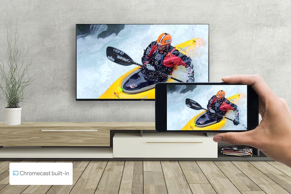 Изображение гостиной, на котором видно телевизор и руку, держащую смартфон. На обоих экранах — одно изображение каякинга.