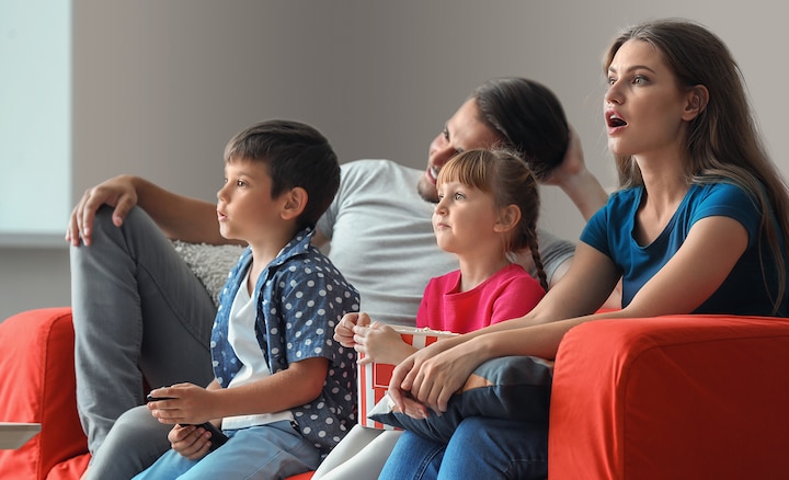 Семья на диване смотрит телевизор